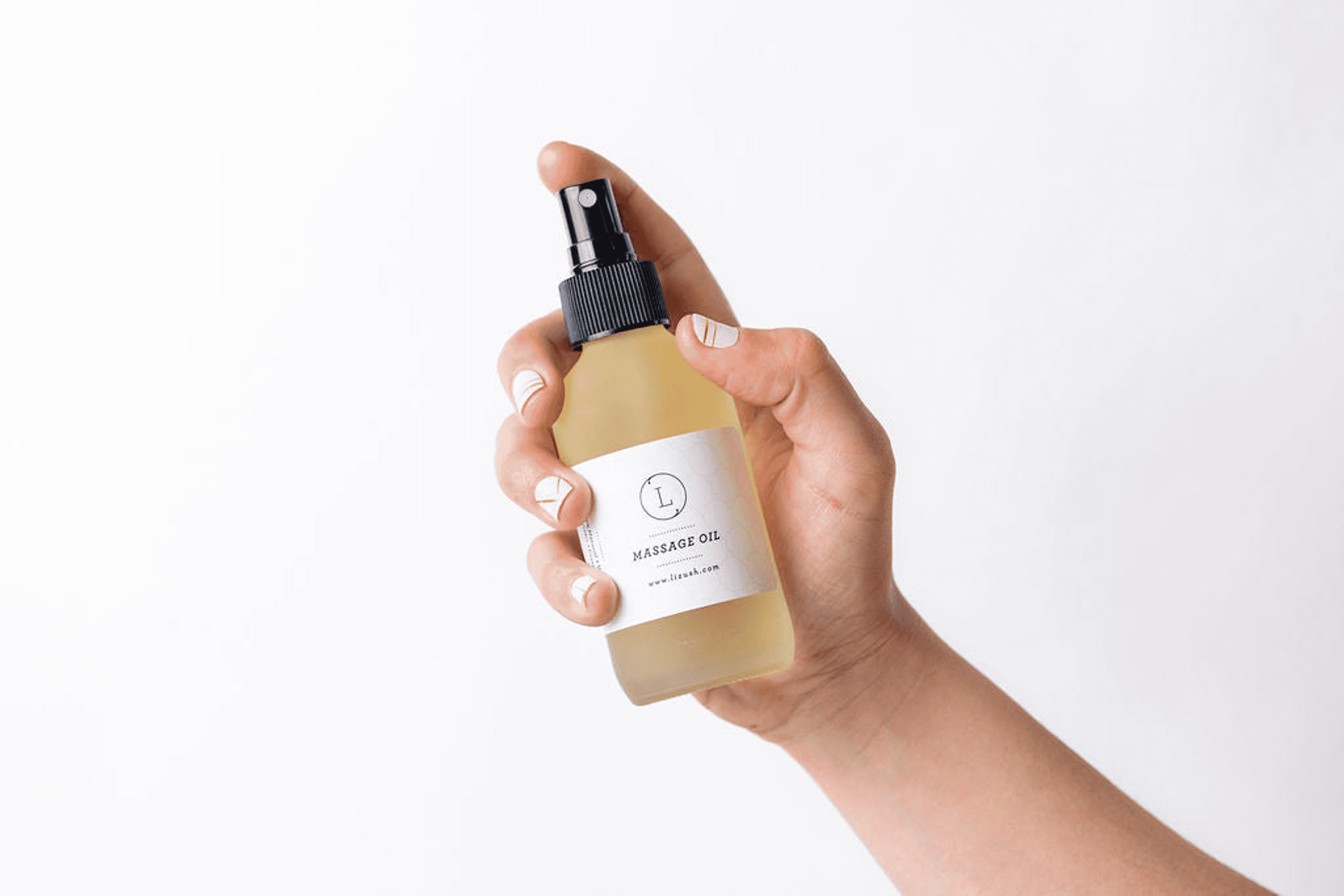 Hand holding massage oil dropper bottle with beige label, small glass vial