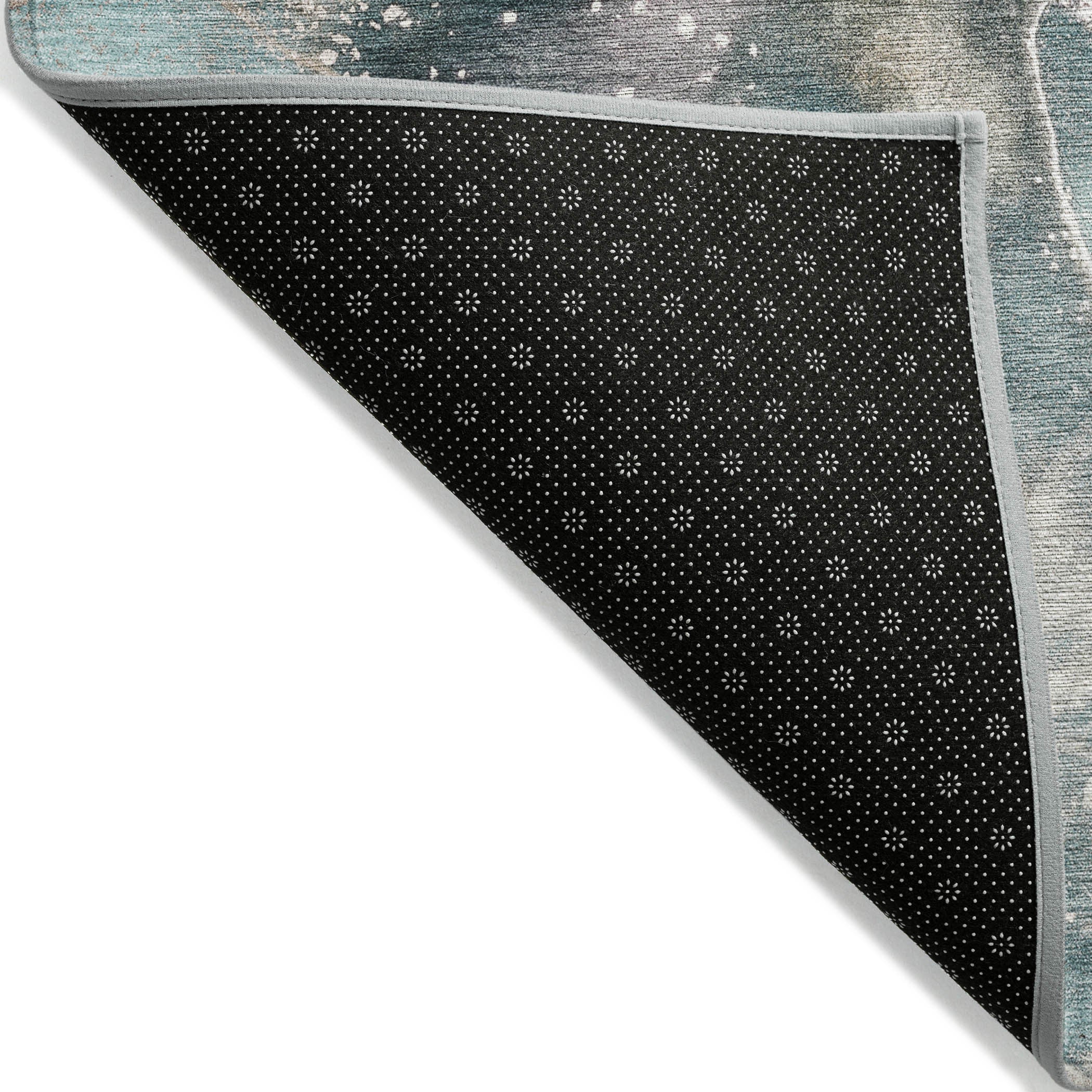 Teal rug backing with black non-slip dotted pattern and light gray edge trim