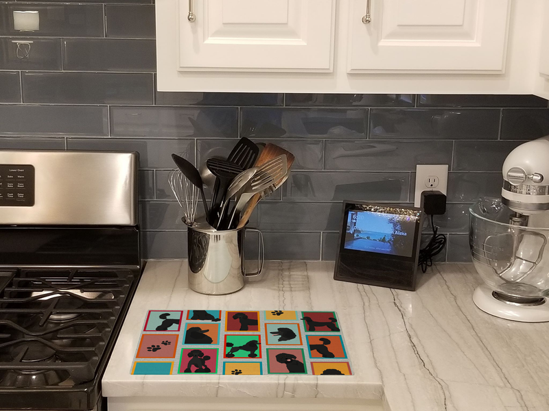 Cutting board on kitchen counter with black poodle silhouette and paw-print design.