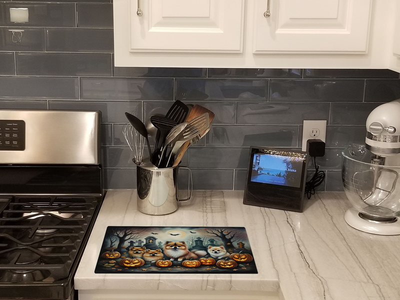 Glass cutting board with Halloween Pomeranian pups on a kitchen countertop
