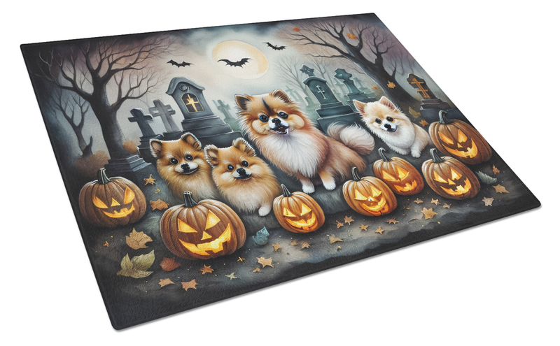 Glass cutting board featuring Pomeranian dogs among pumpkins and tombstones