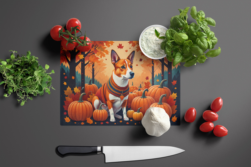 Glass cutting board with basenji dog, pumpkins, and autumn leaves; knife nearby
