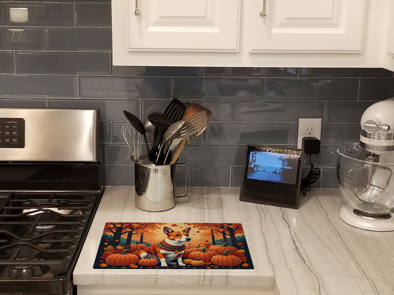 Glass cutting board with basenji dog and pumpkins, shown on kitchen countertop