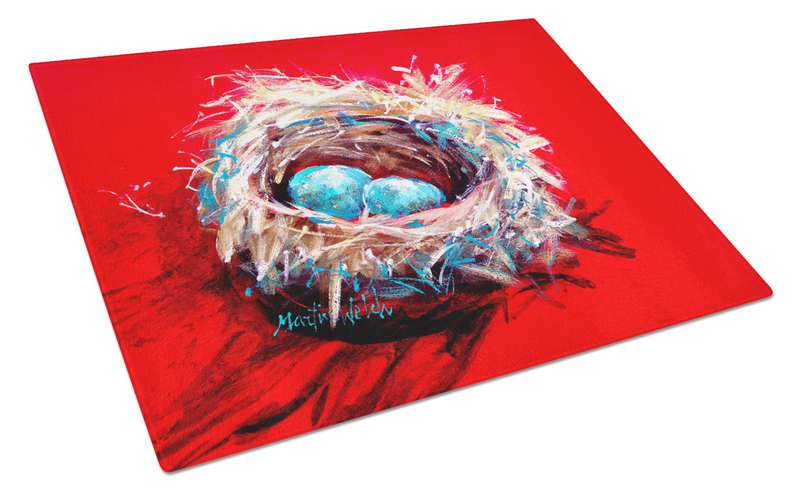 Glass cutting board with bird nest and blue eggs artwork, angled view on red