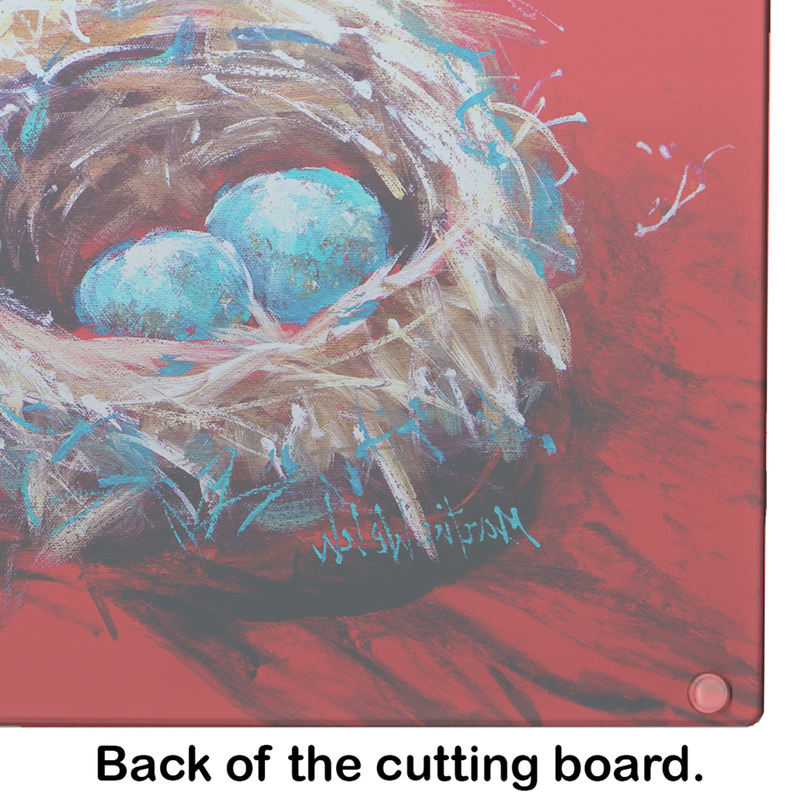 Glass cutting board close-up of bird nest and blue eggs artwork on red surface