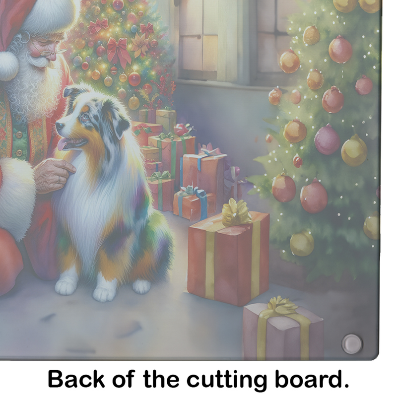 Glass cutting board close-up with Santa and Australian Shepherd beside wrapped gifts.