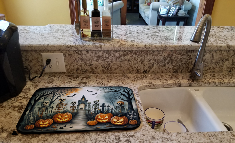 Skeleton Halloween dish drying mat on kitchen counter beside sink, rectangular printed design