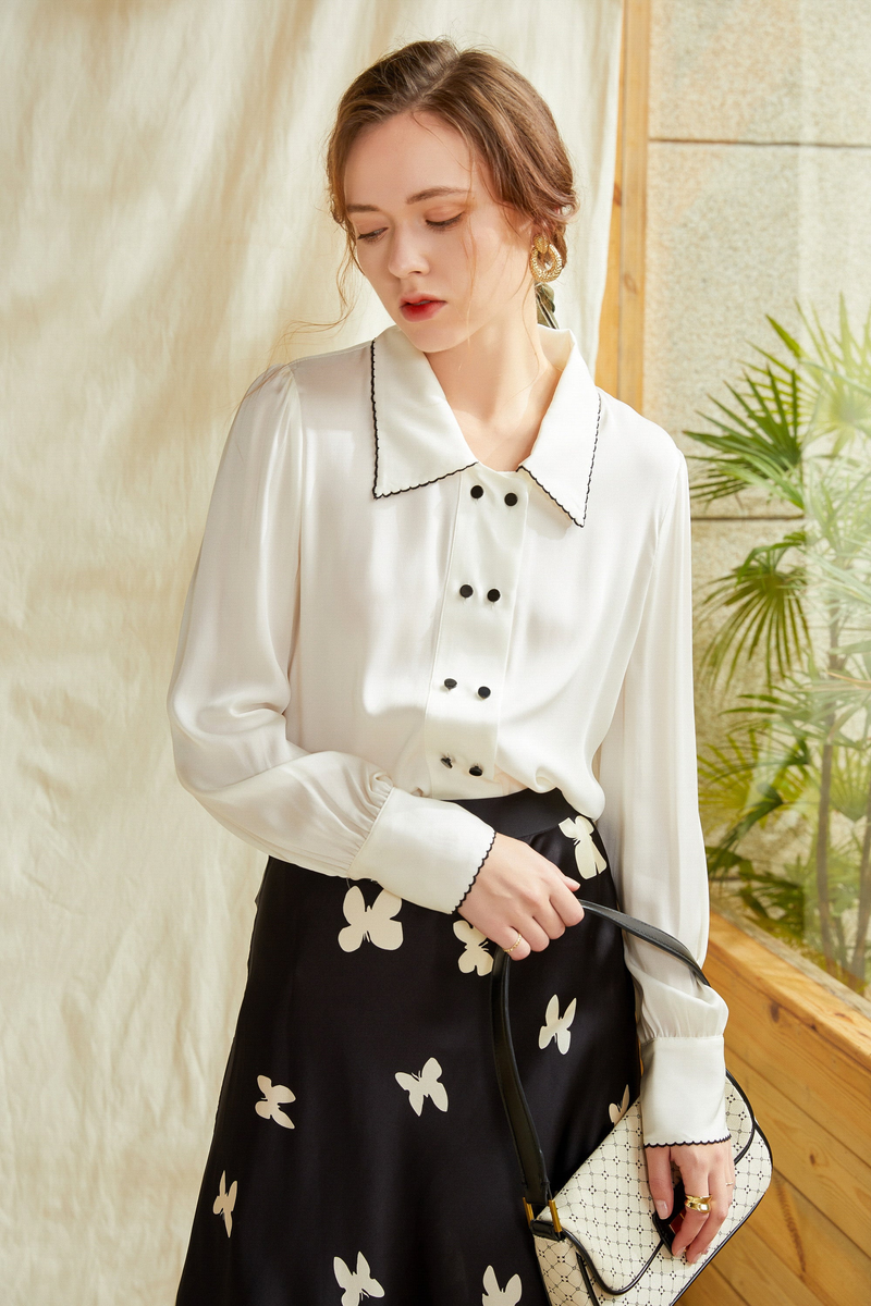 Ivory silk button-up shirt with contrast point collar, dark buttons, and buttoned cuffs