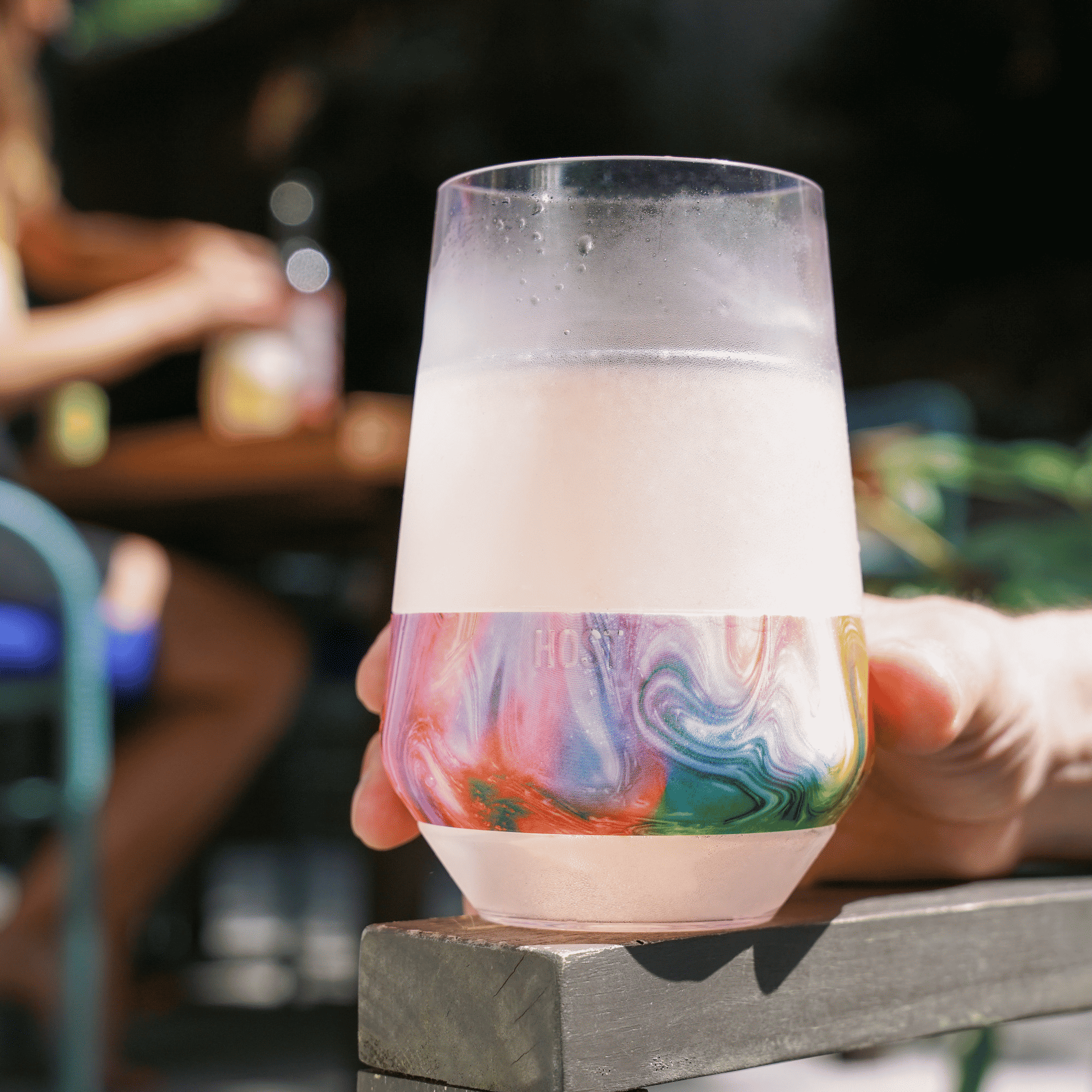 Hand holding wine cooling cup with condensation and colorful band
