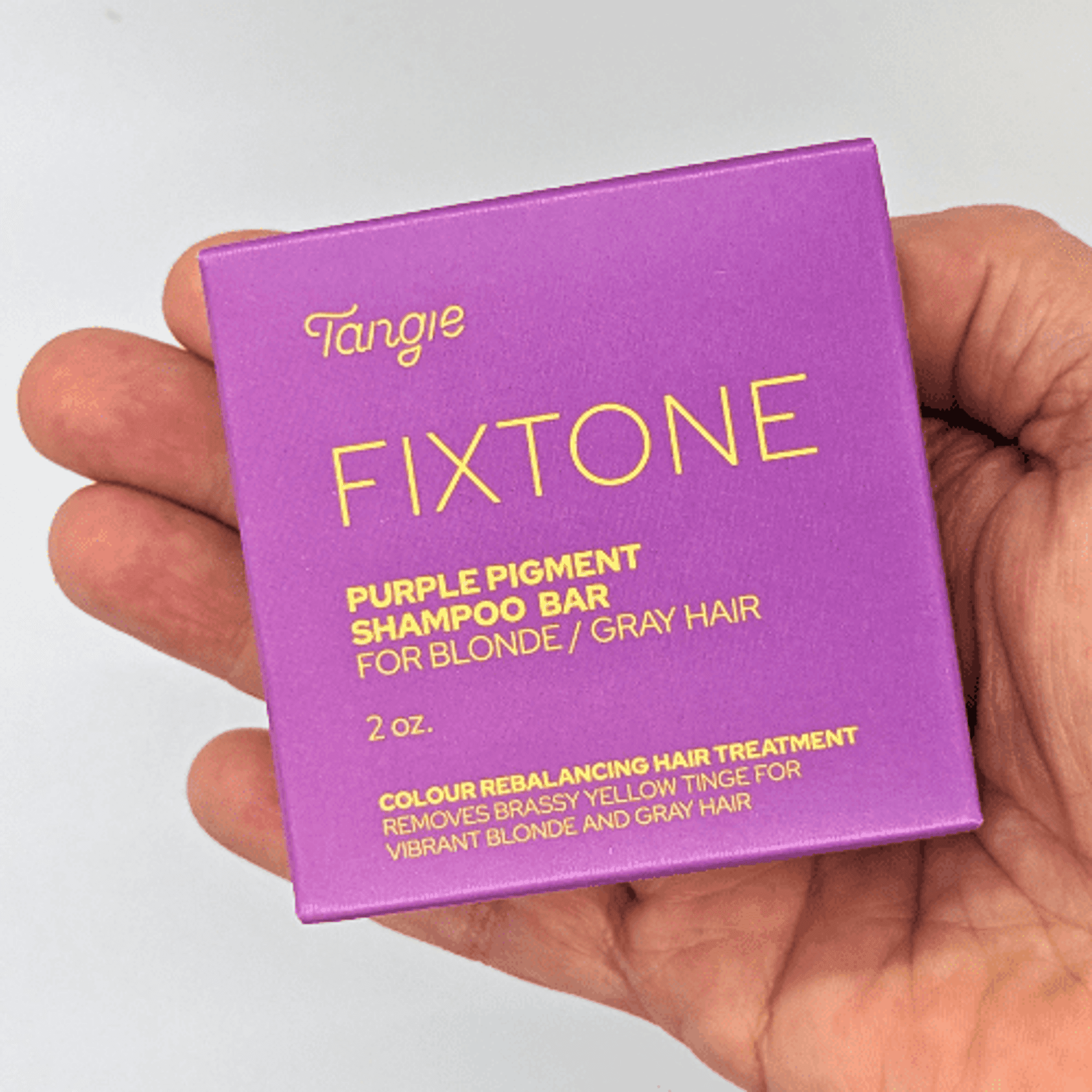 Purple pigment shampoo bar box for blonde/gray hair, shown in hand
