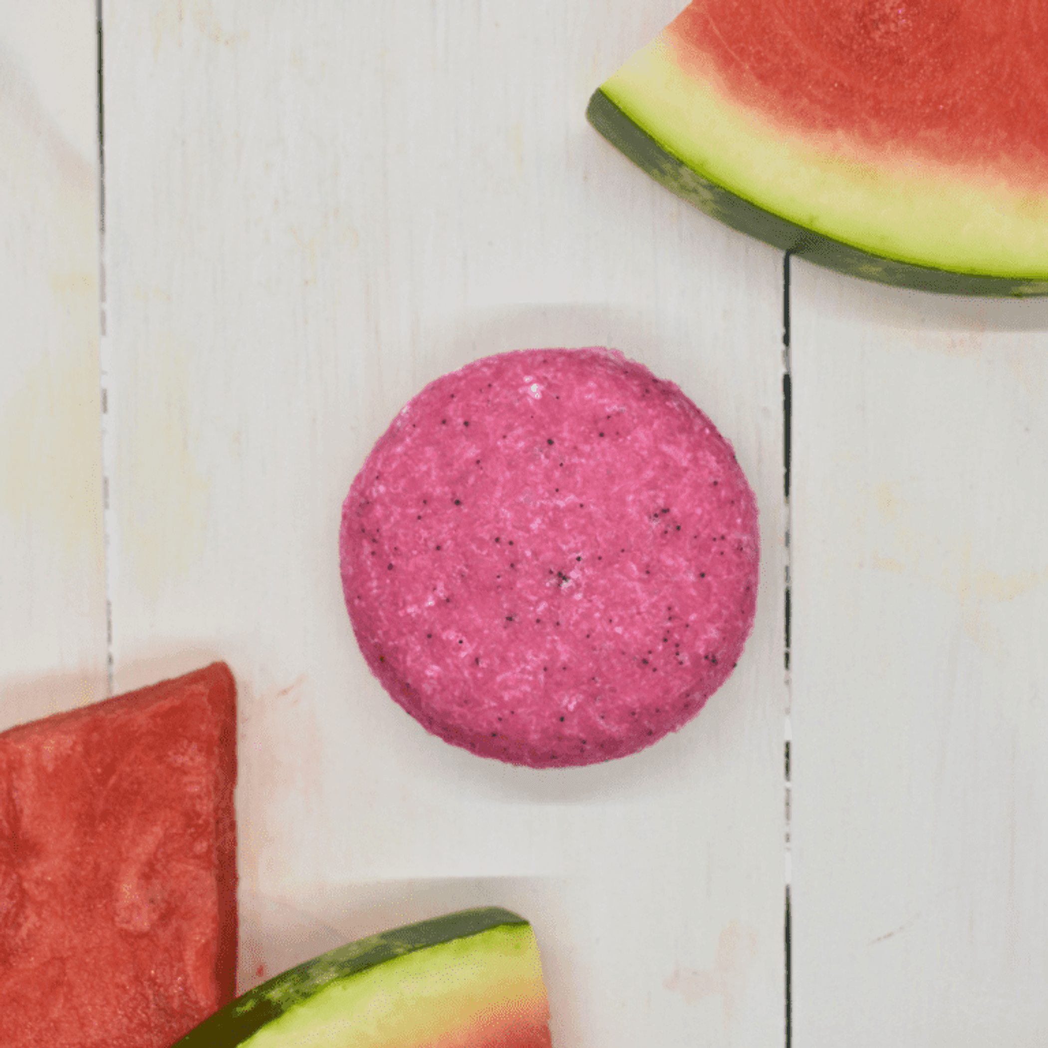 Pink shampoo bar on white board beside watermelon slices