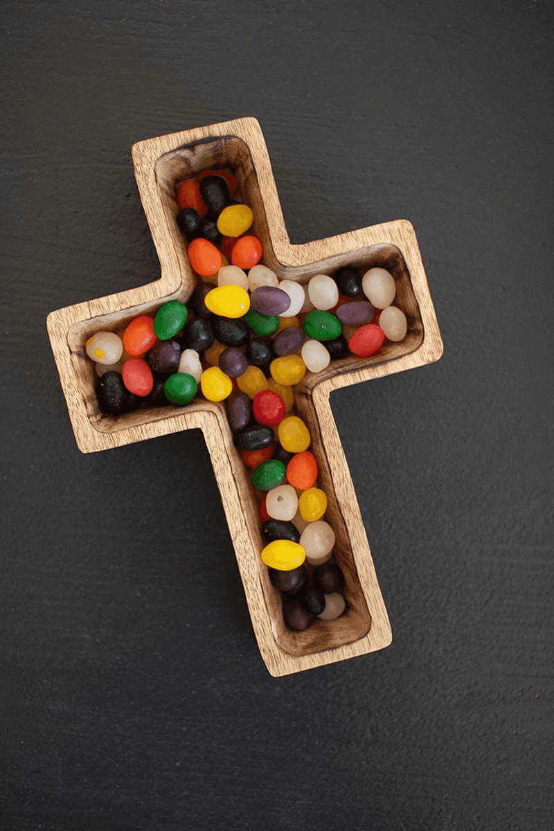 Brown wooden cross-shaped bowl filled with colorful beads