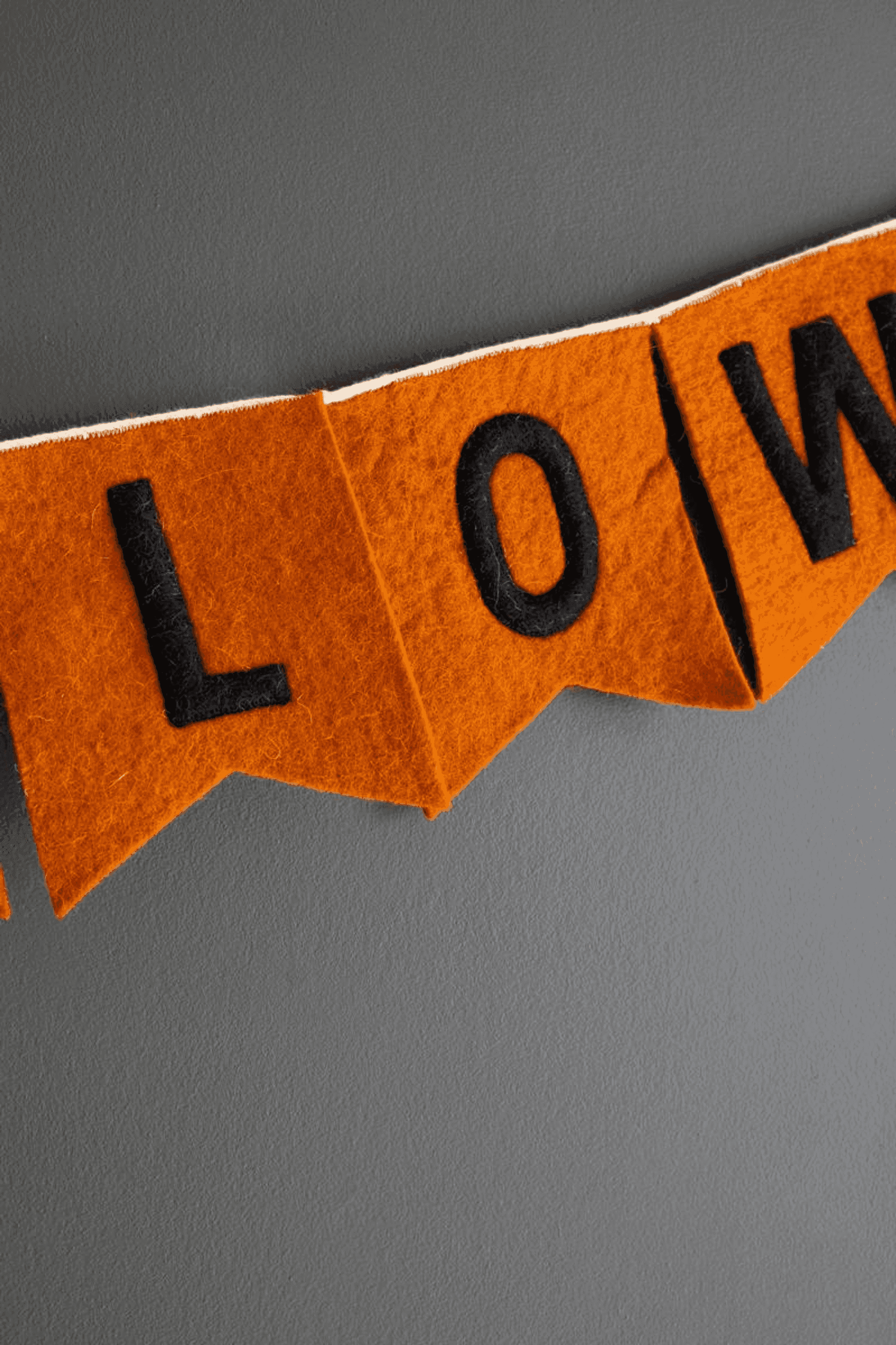Orange felt Halloween garland banner with black 'LOWEEN' letters on flags