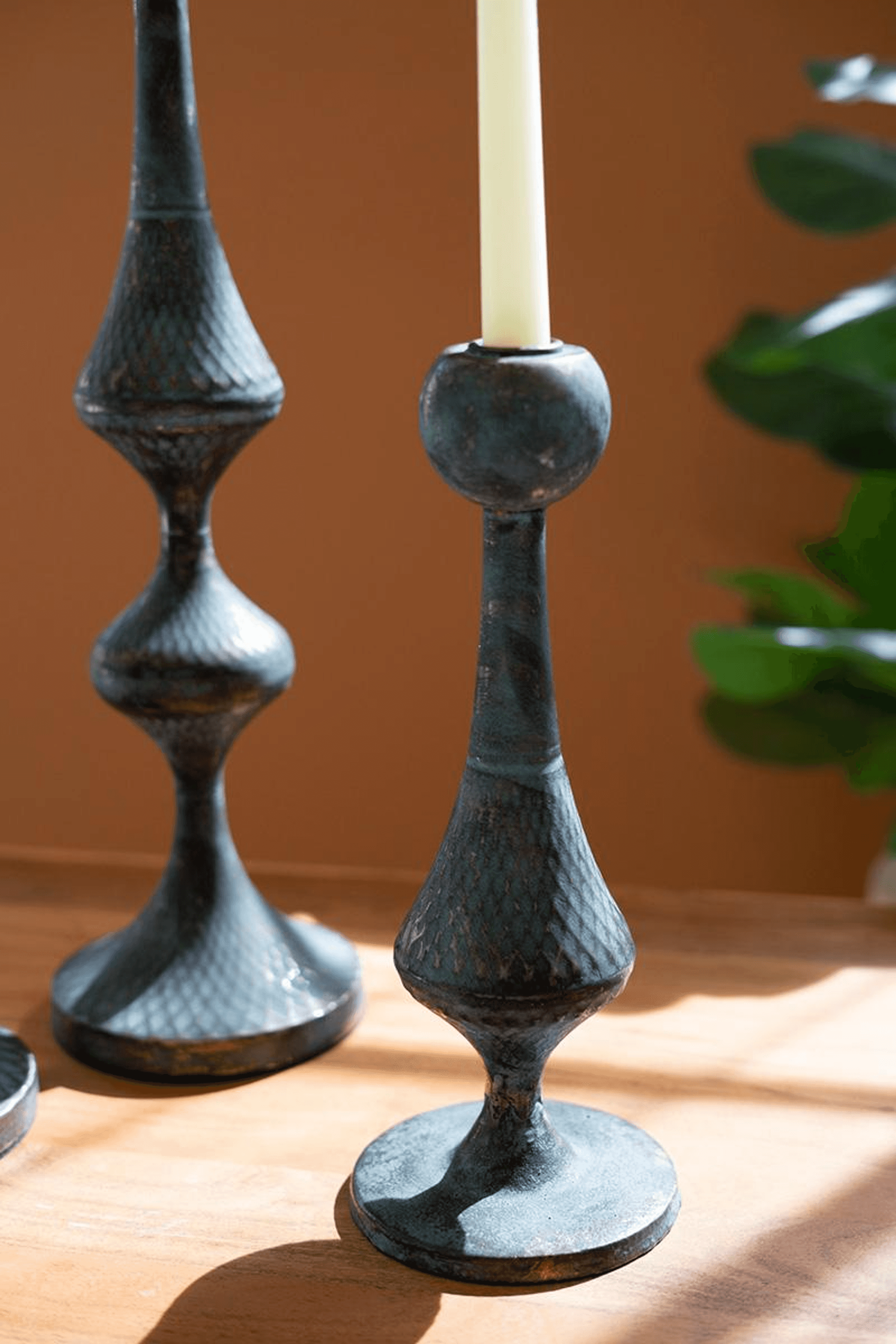 Metal candle tower holder with white candle, dark blue-gray textured finish