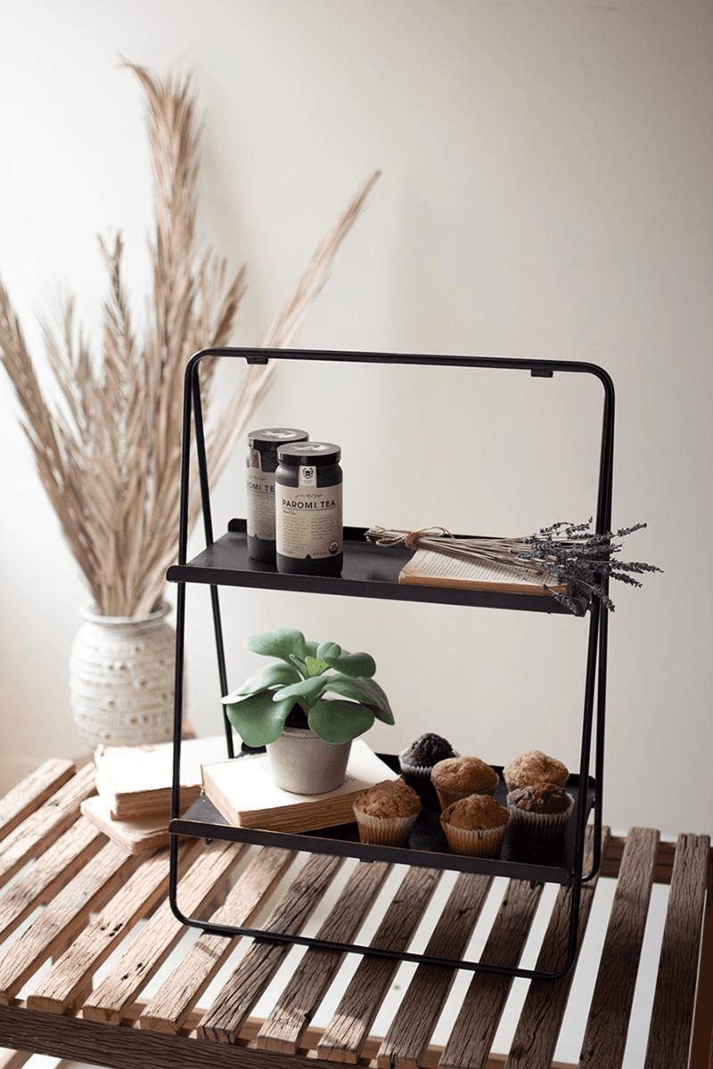 Black two-tier rectangle display rack with plant pot and small items on both shelves.