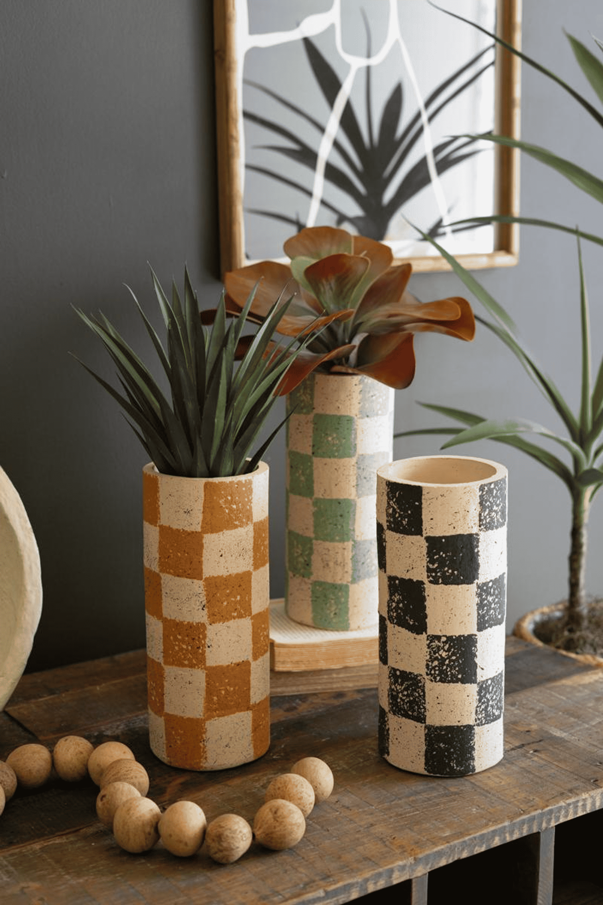 Three checked clay cylinder vases: orange, green, and black-and-cream patterns