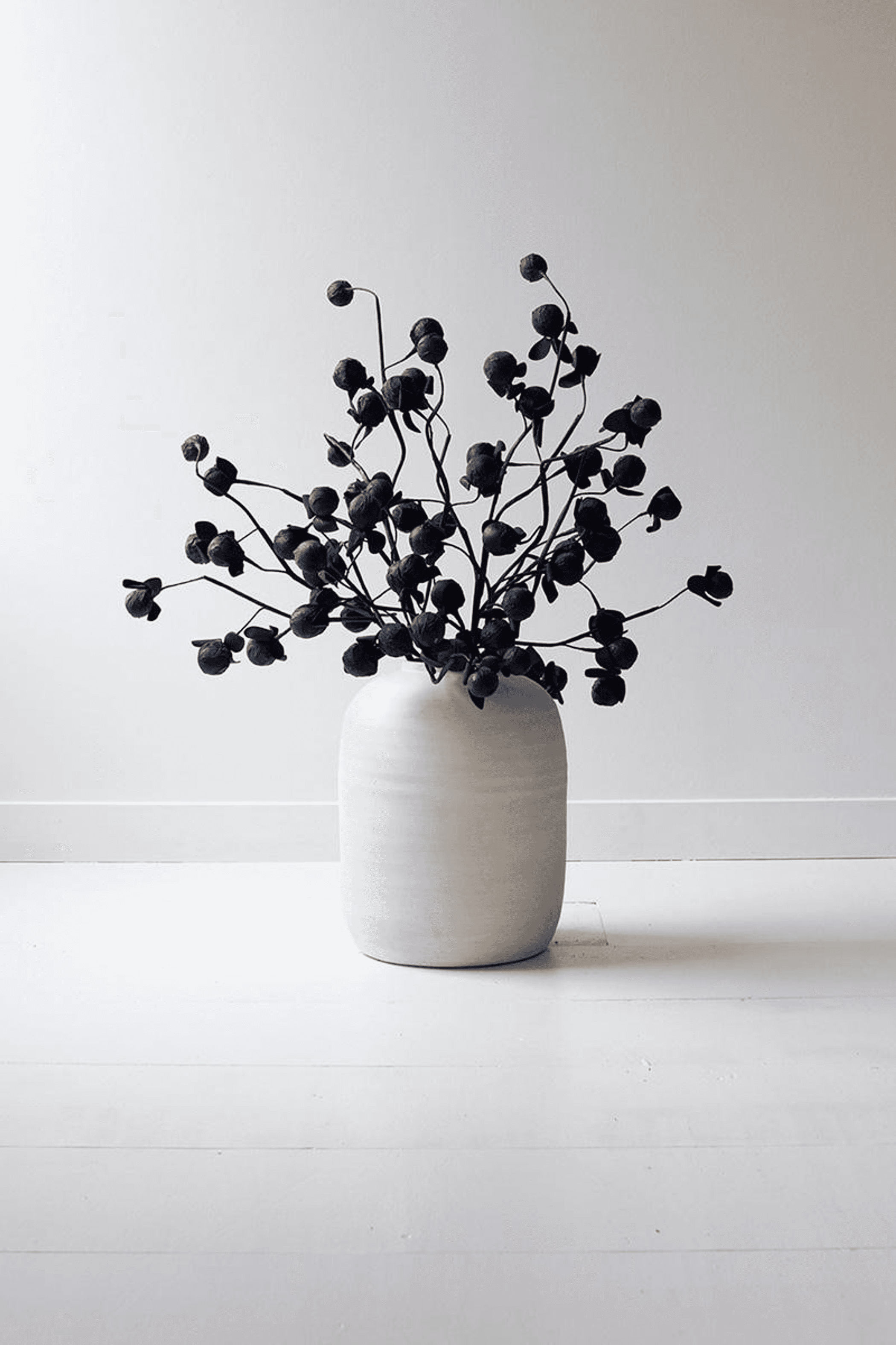 Black bud-filled floral arrangement in a ceramic vase