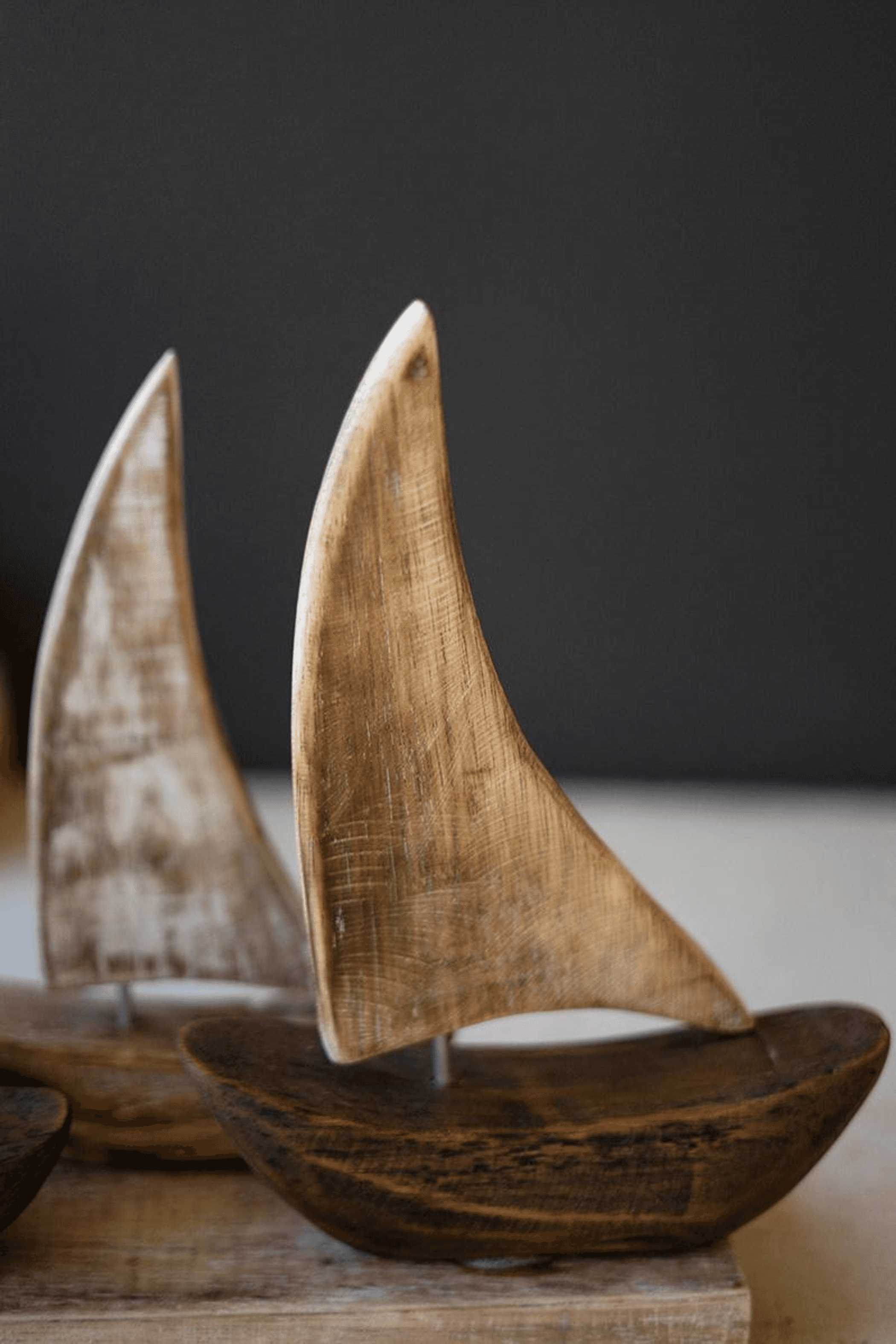 Wooden sail boat set with curved hulls and tall sails on a base
