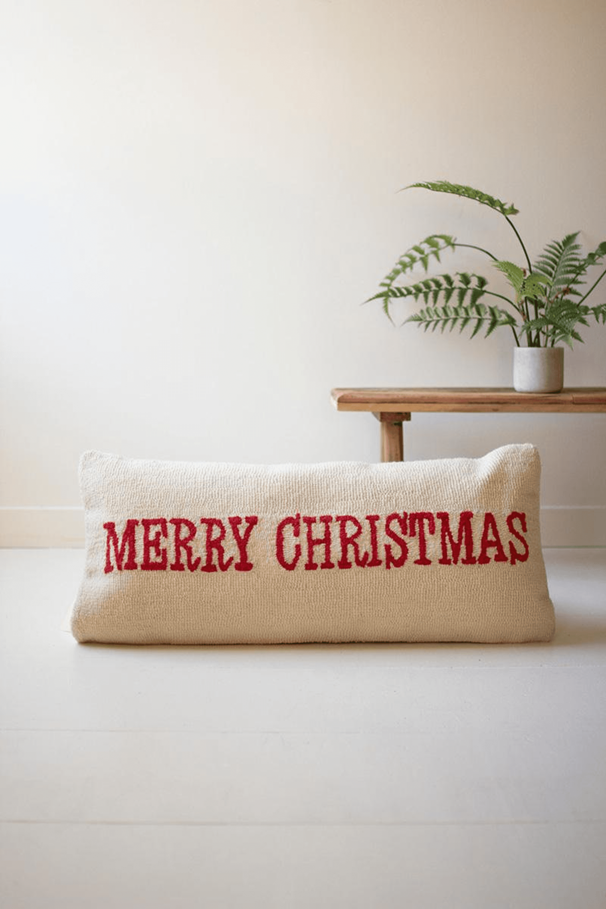 Cream hand-hooked pillow with bold red 'MERRY CHRISTMAS' lettering