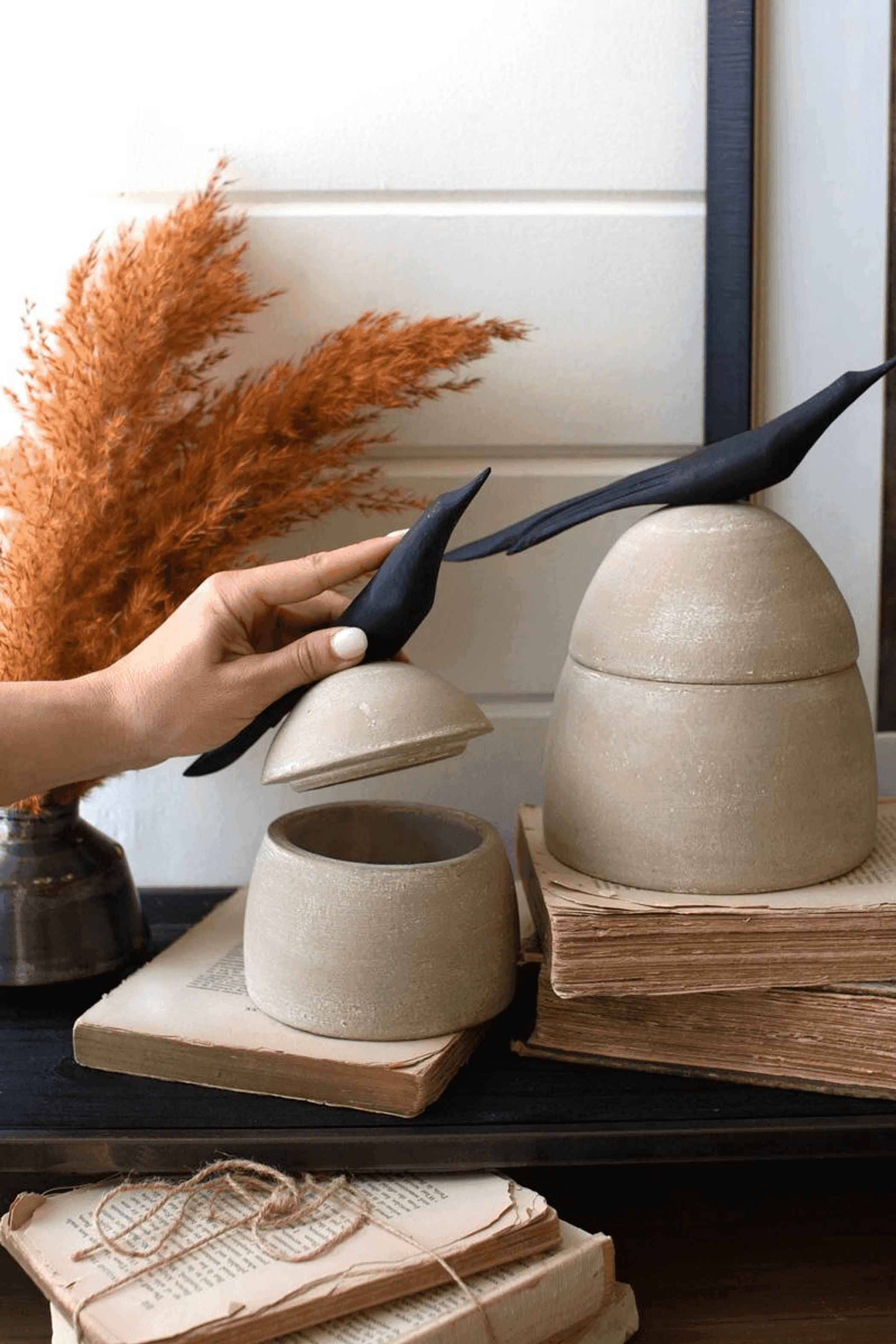 Tan clay canisters with black bird handles, one small canister beside it
