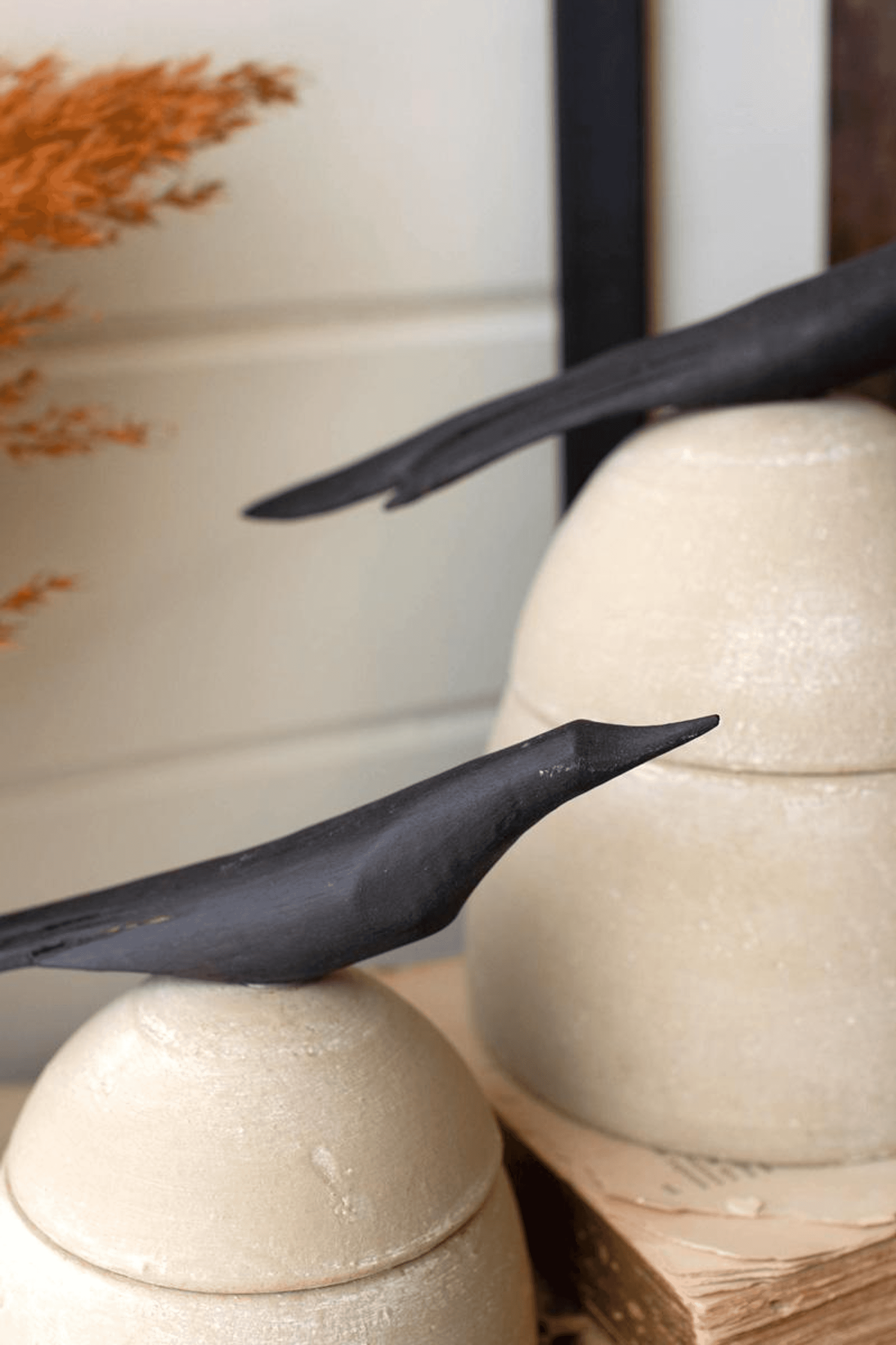 Close-up: tan clay canisters with black bird-shaped handles and rounded lids