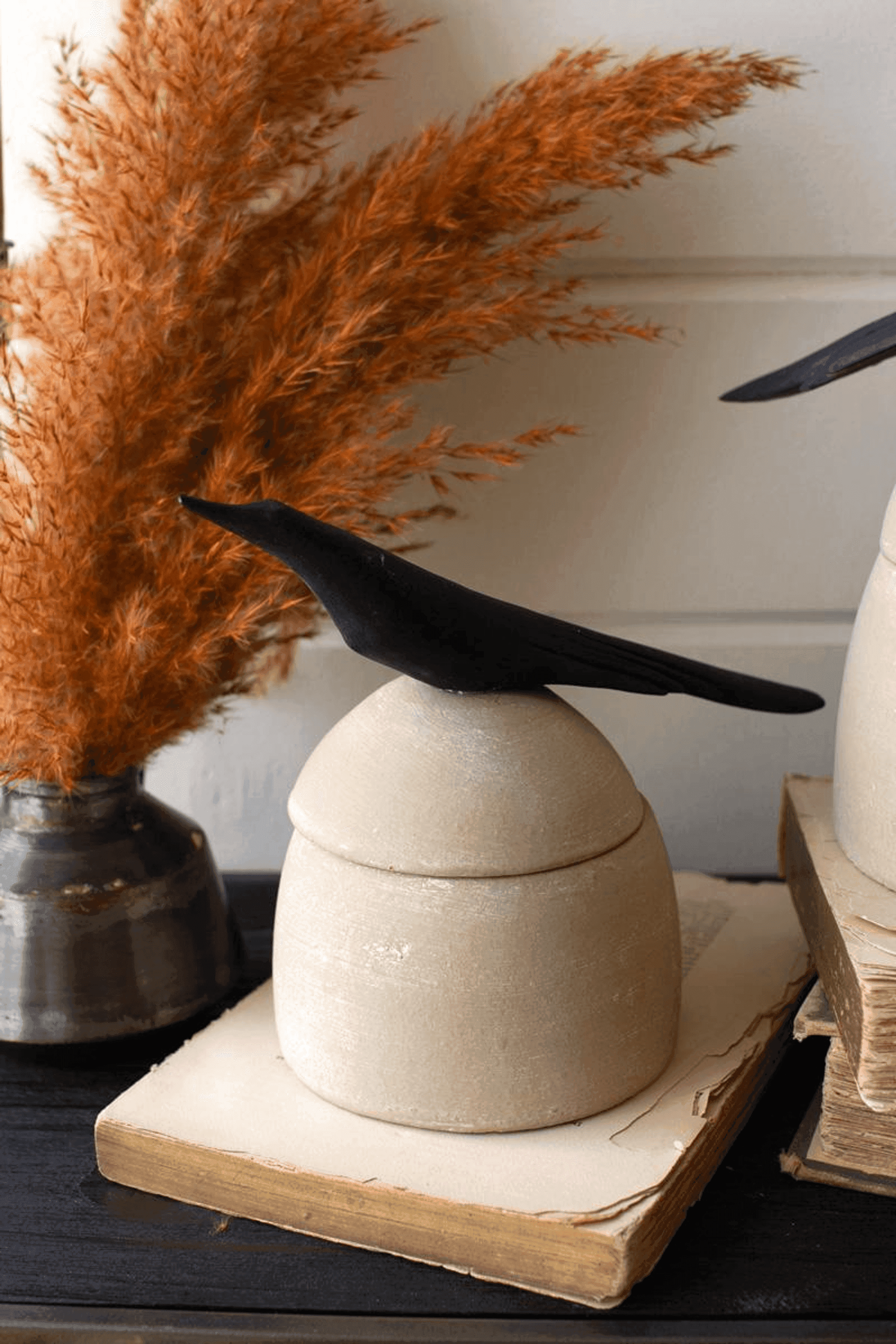 Tan clay canisters with black bird handles on wooden boards