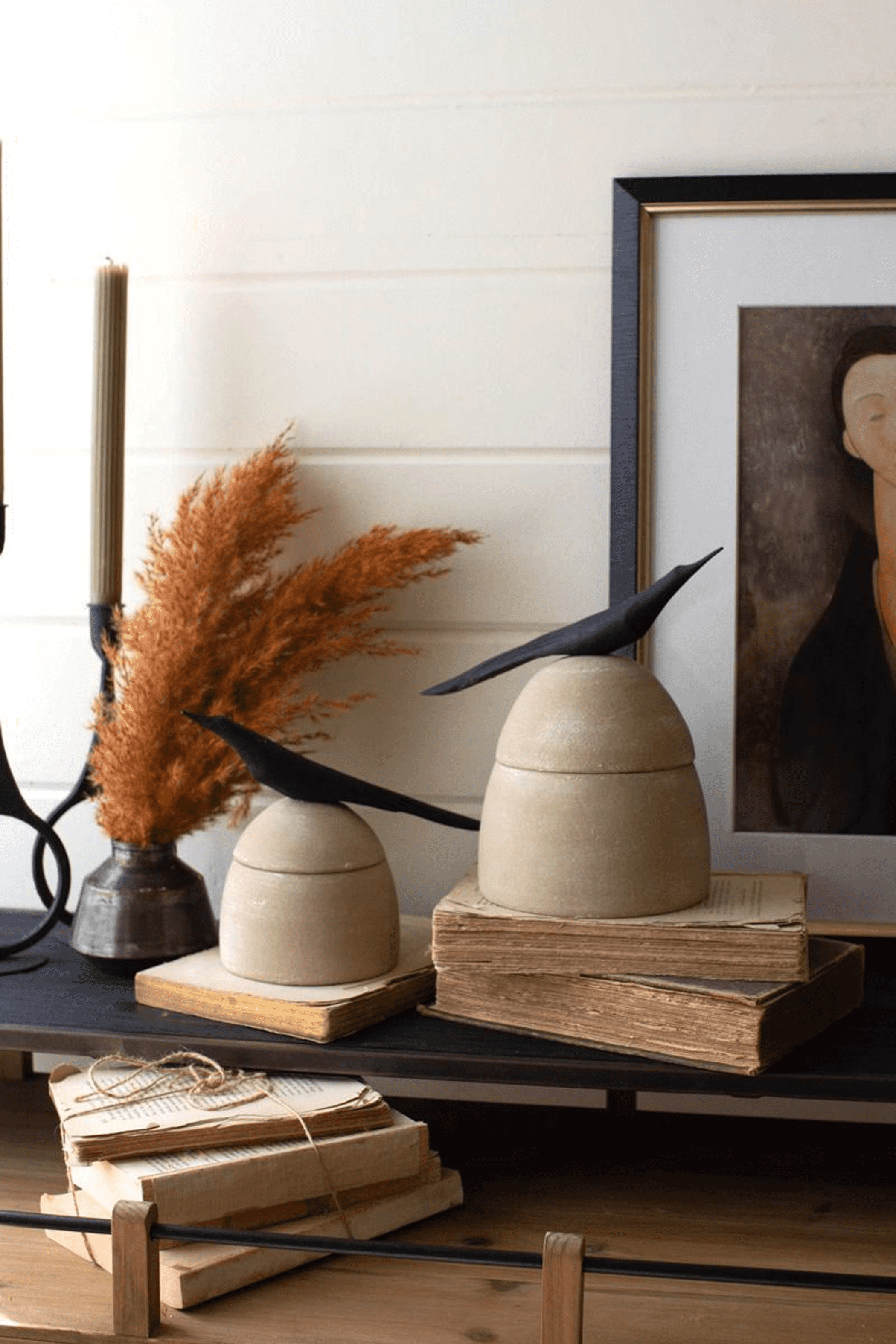 Two tan clay canisters with black bird handles on wooden display boards
