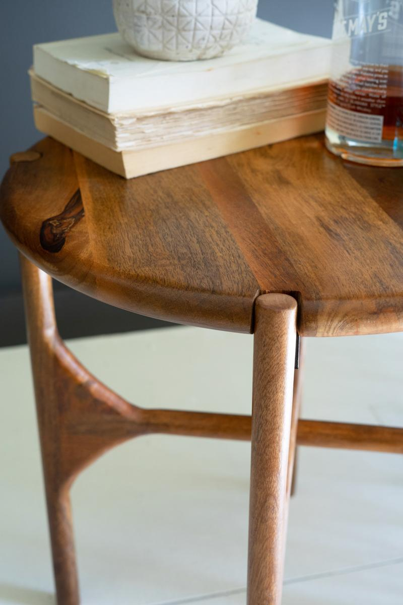 Round mango wood accent table close-up of curved edge and turned leg