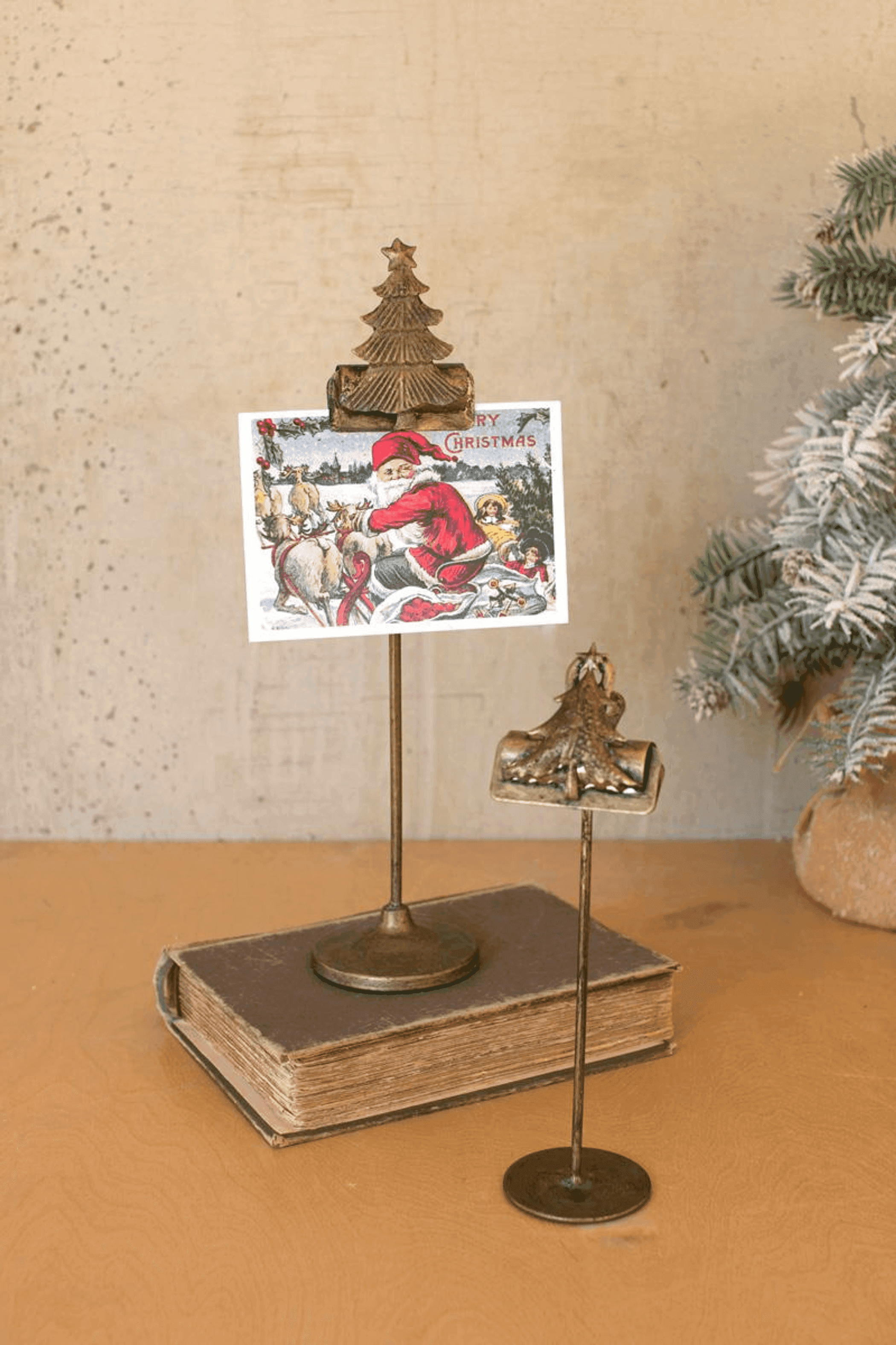 Set of two gold Christmas tree card clips on tall stands holding decorative cards