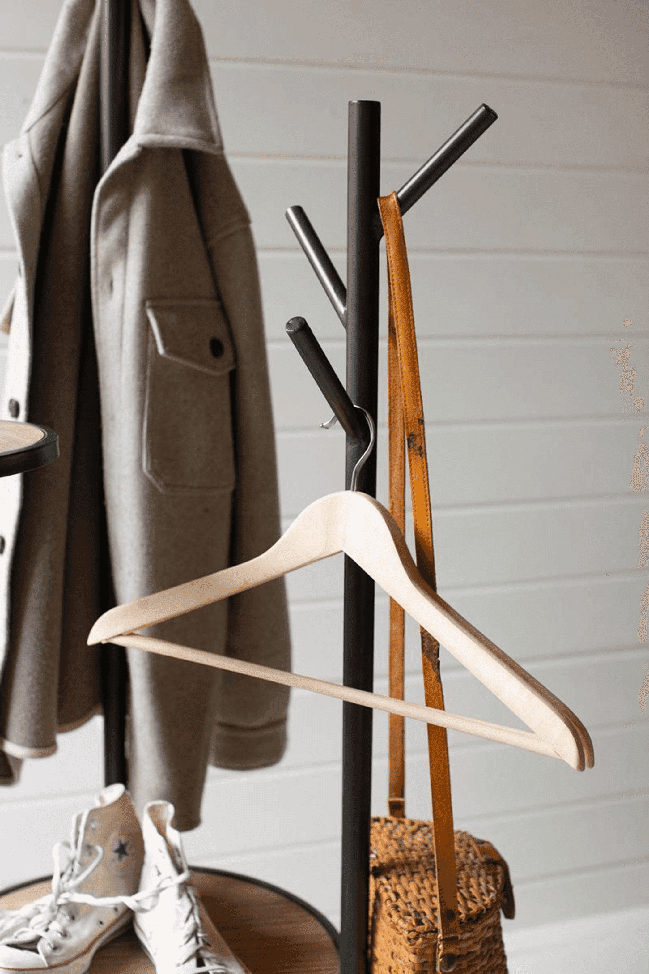 Gray coat rack with round shelves and angled hooks, with a light-wood post and hangers.