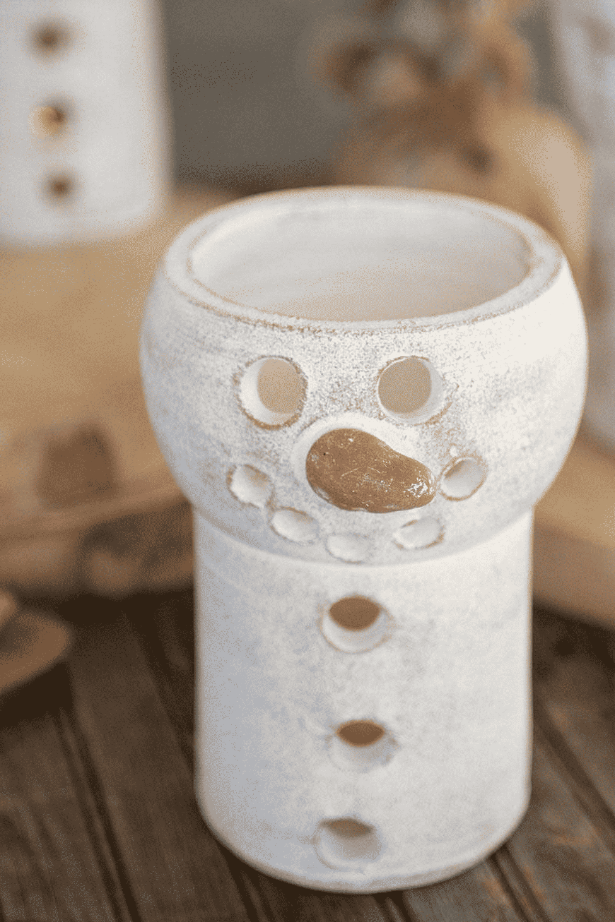 White ceramic snowman luminary with cutout face and oval lantern opening