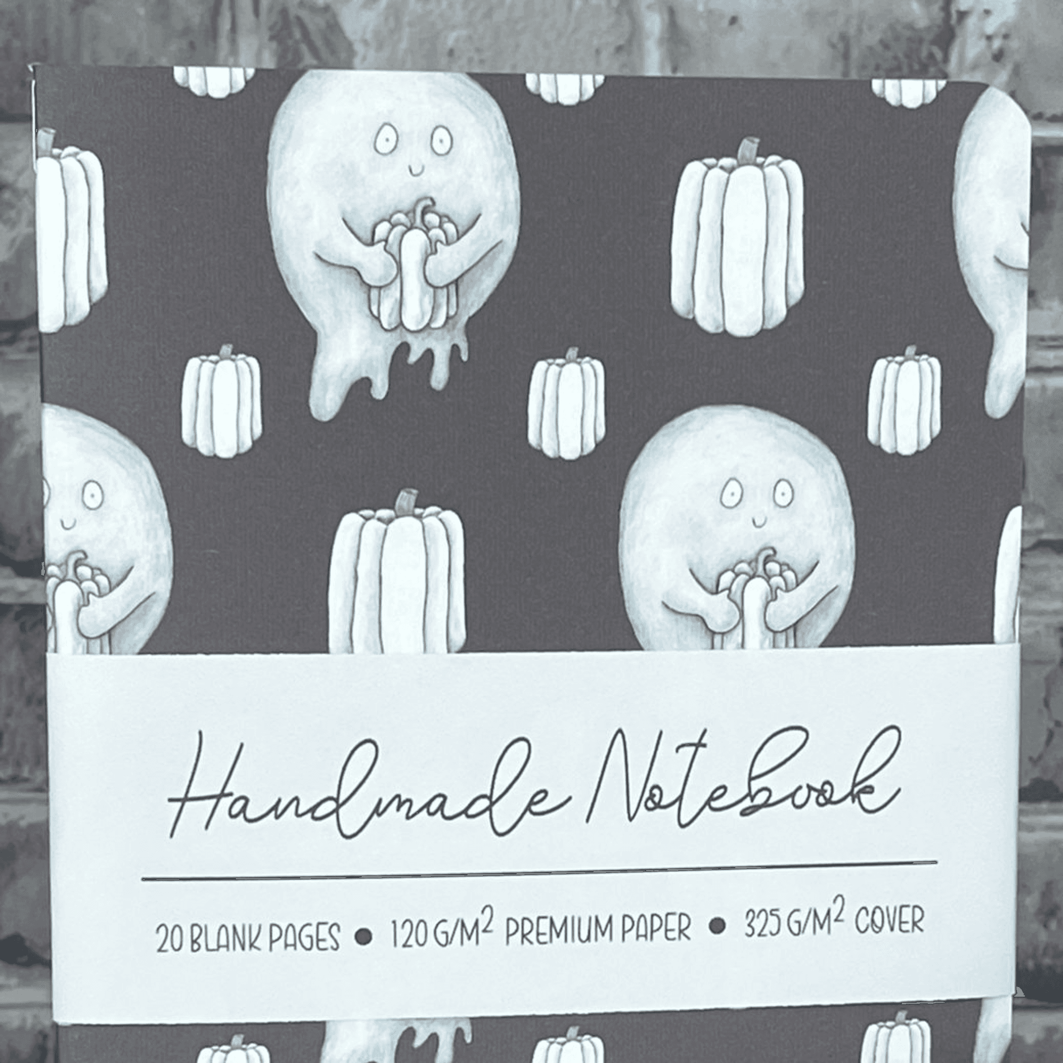 Handmade notebook front cover with light blue ghosts and pumpkins on a dark background