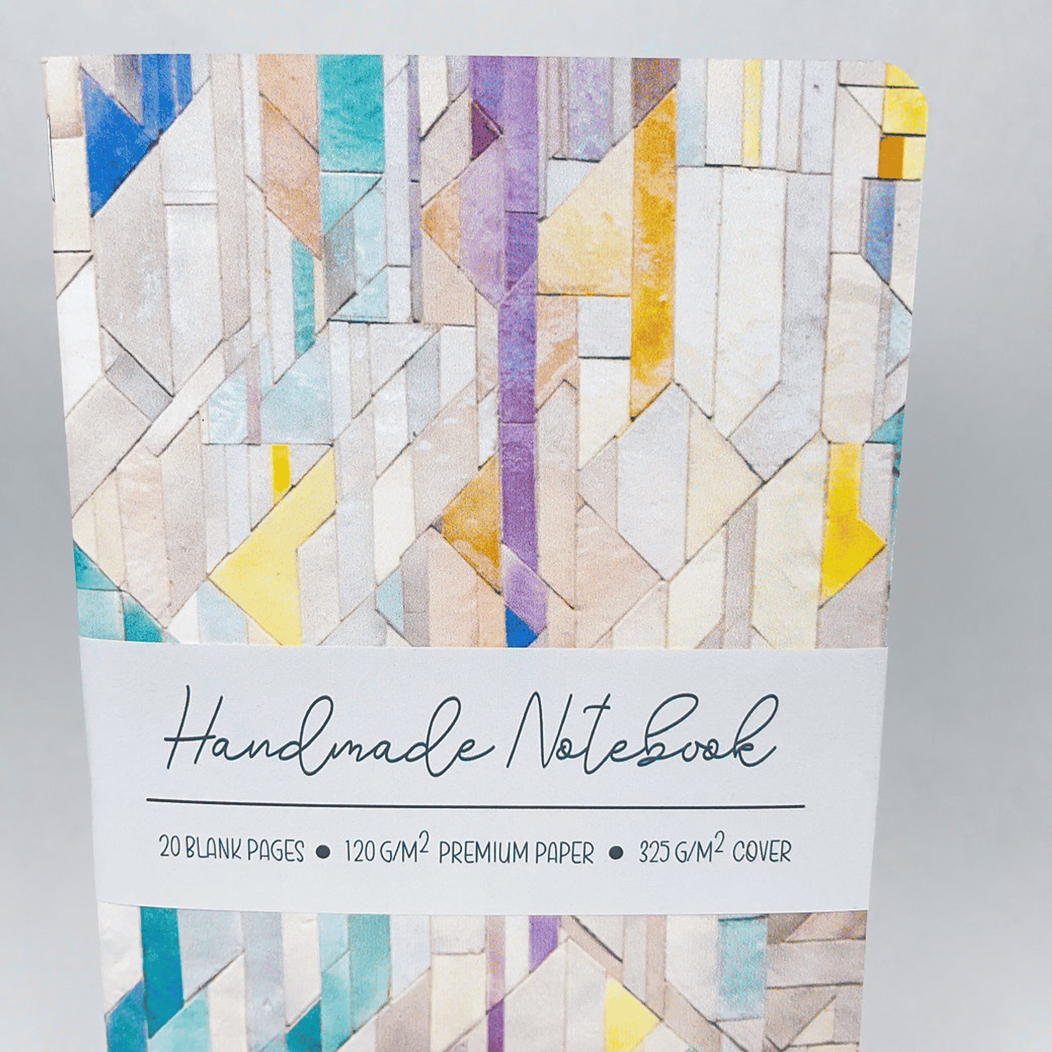 Handmade notebook with geometric tile cover and centered white label strip.