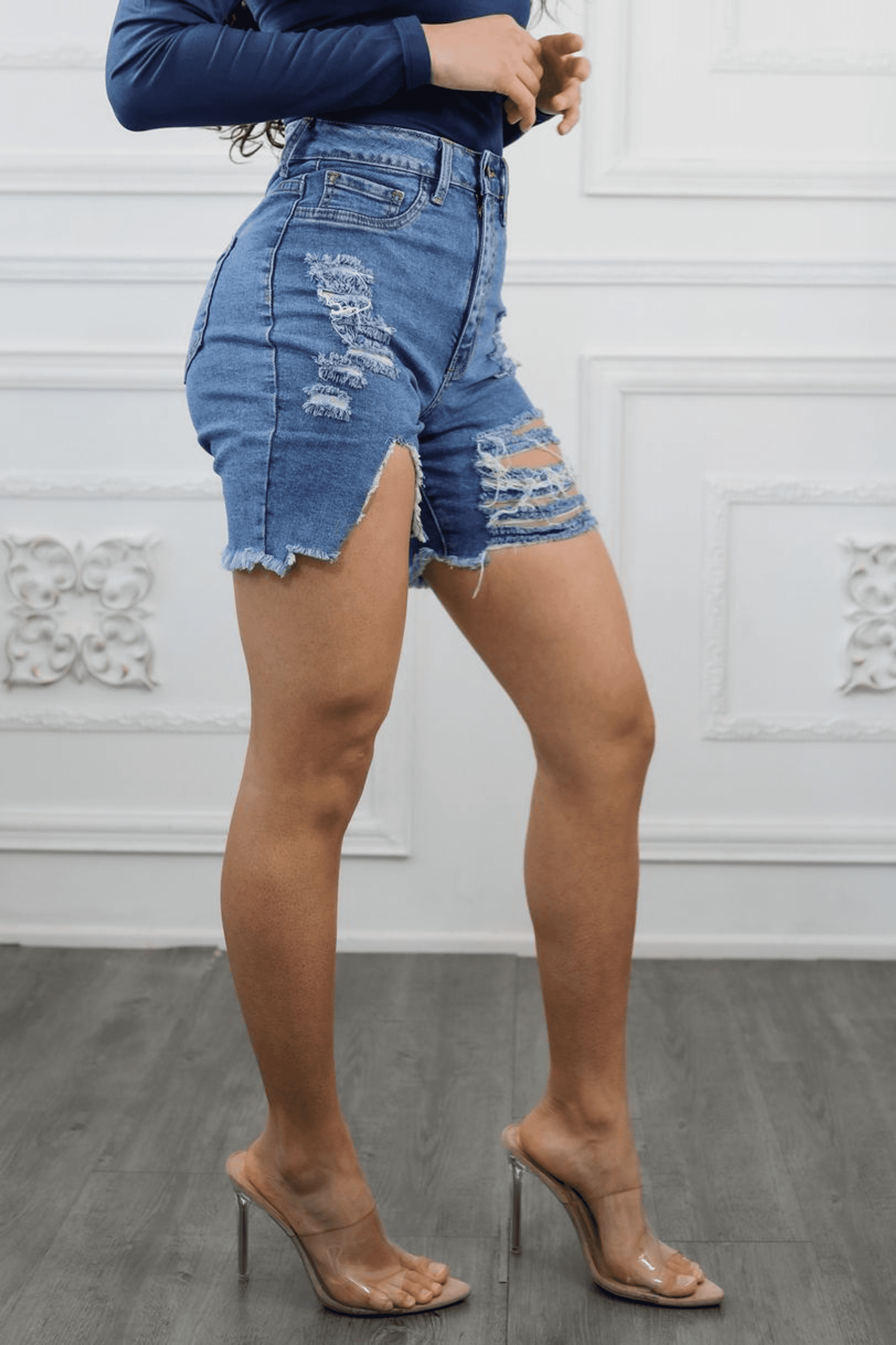 Women’s distressed cut-out high waist denim shorts, side view with frayed leg openings