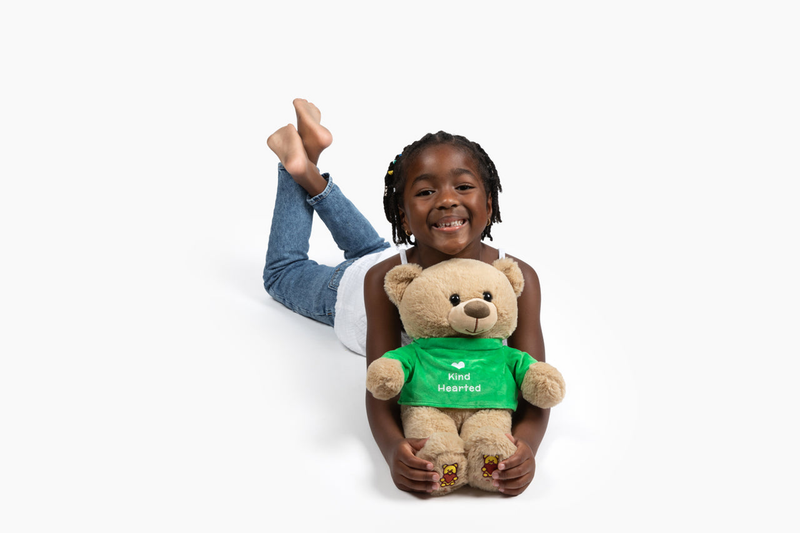 Bene Bear Kit beige plush bear in green shirt, held by child