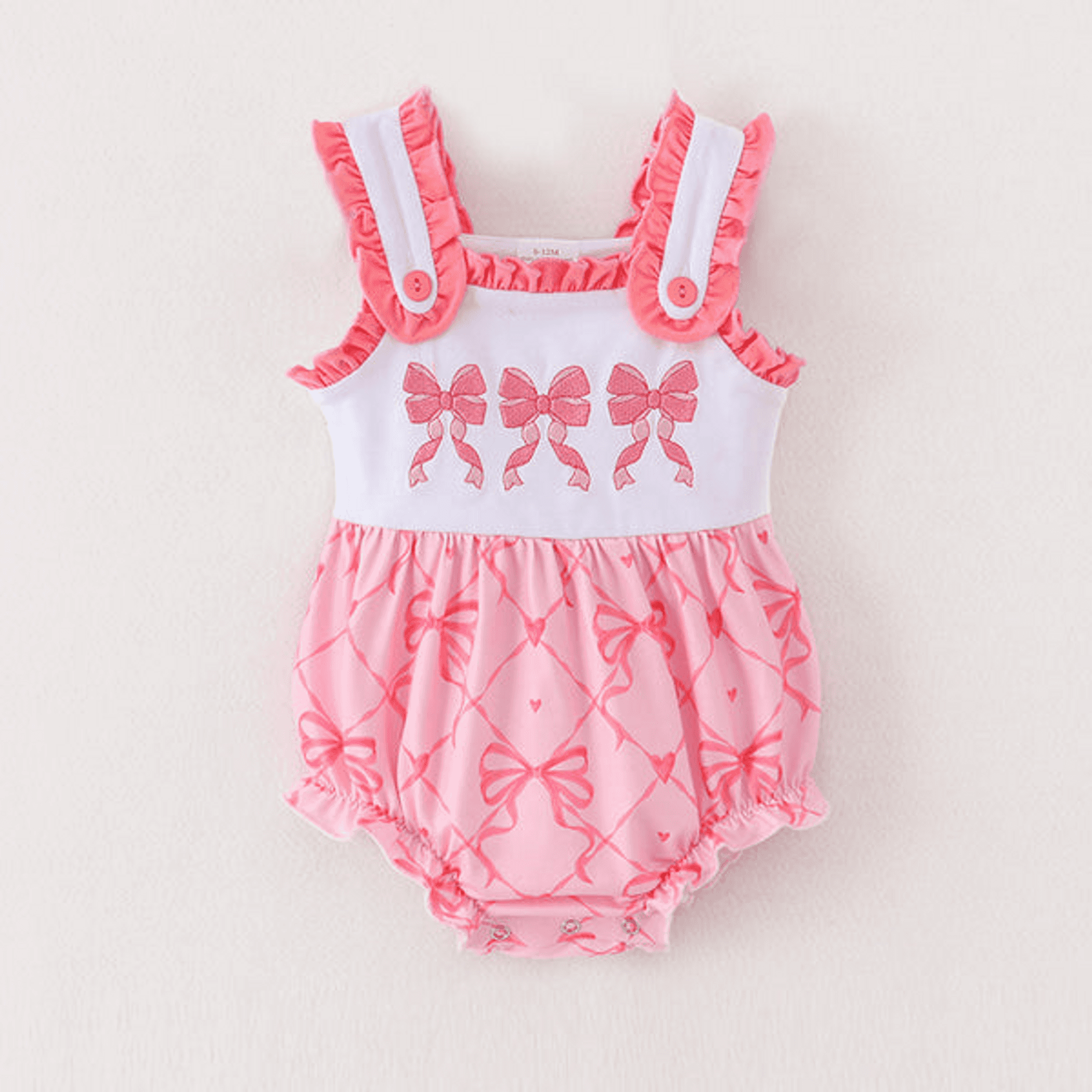 Pink and white baby romper with ruffled straps and bow-patterned bodice
