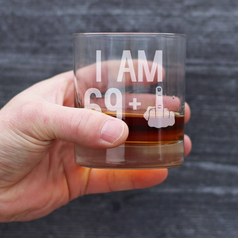 Close-up of I AM 69+ middle finger whiskey rocks glass with amber drink inside.