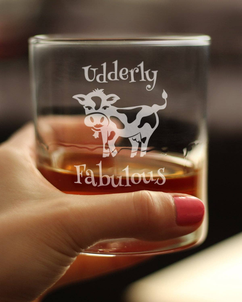 Whiskey rocks glass held in hand, showing “Udderly Fabulous” cow etching