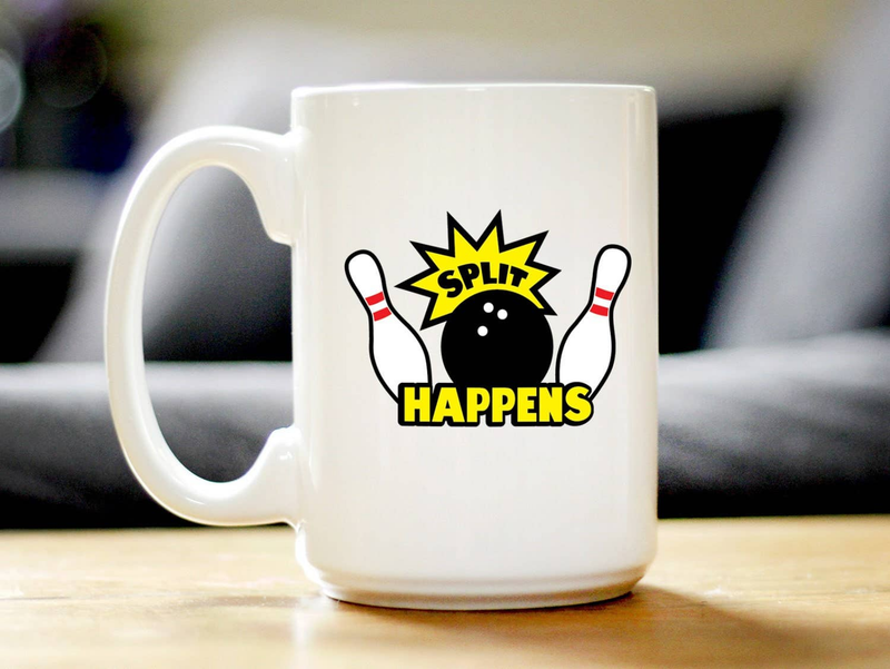 White ceramic coffee mug with "Split Happens" bowling graphic, on a table surface
