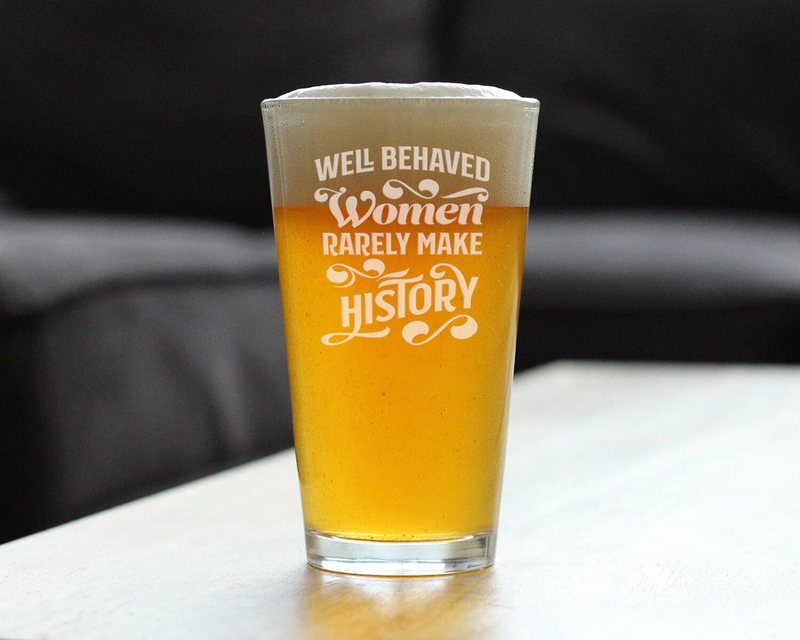 Beer pint glass with etched feminist slogan, amber beer standing on surface