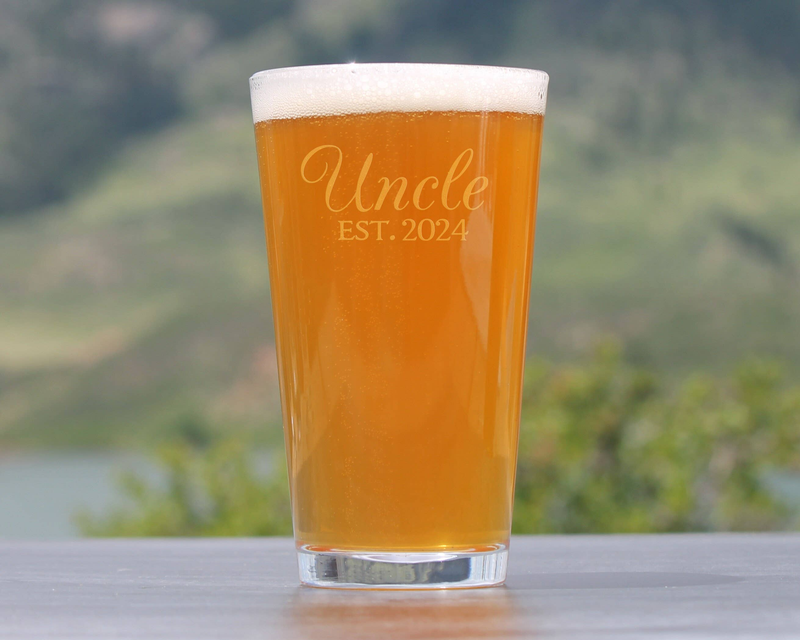 Uncle EST. 2024 etched pint glass with amber beer and foam top