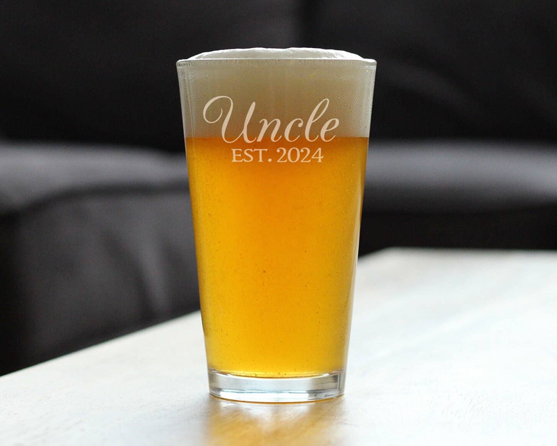 Clear pint glass with Uncle EST. 2024 engraving, filled with amber beer