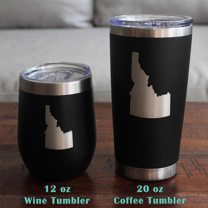Set of two black insulated tumblers with etched Idaho silhouette on a wooden surface