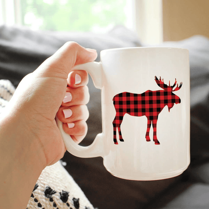 White ceramic coffee mug with plaid moose silhouette, held in hand
