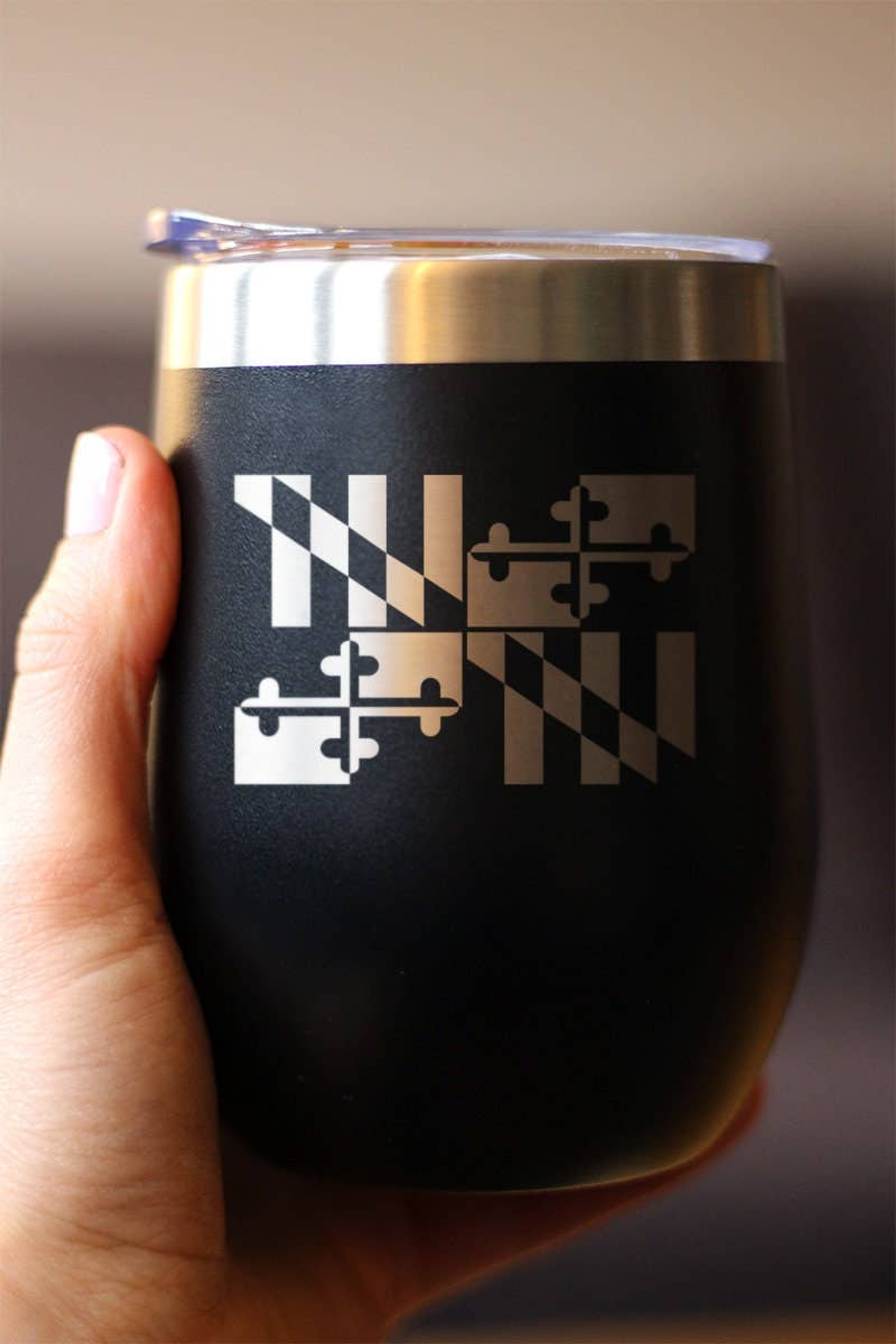 Black insulated wine tumbler with Maryland emblem, held in hand, stainless steel rim