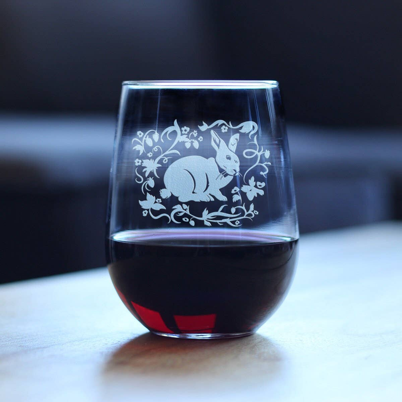 Stemless wine glass with etched rabbit floral design, filled with red wine, close view