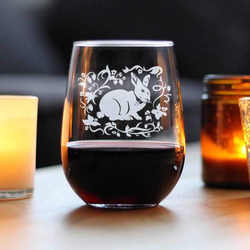 Clear stemless wine glass with hand-etched rabbit and vines, filled with red wine