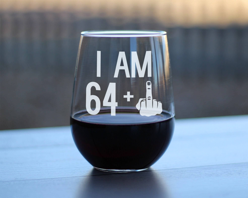 Stemless wine glass with etched "I AM 64" and middle finger graphic, dark wine inside