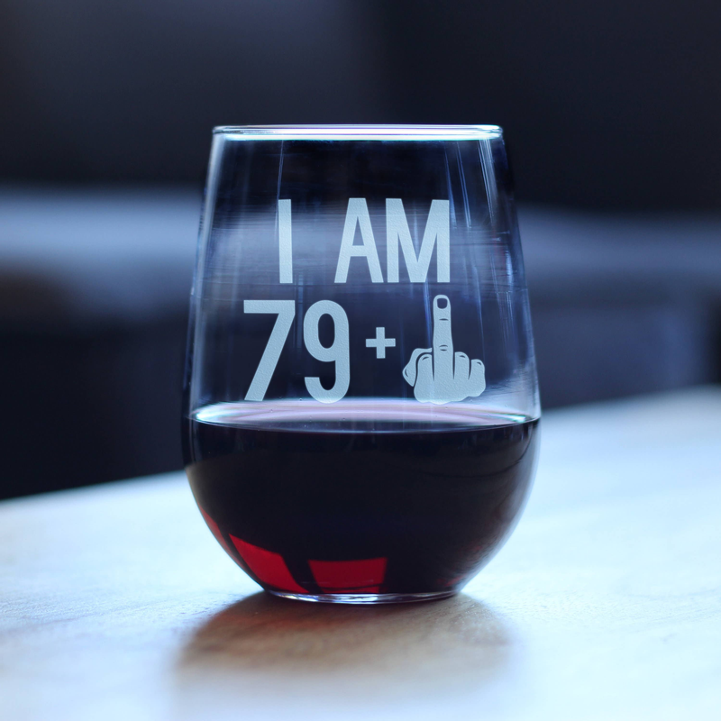 Stemless wine glass filled with red wine, featuring "I AM 79+" etched front