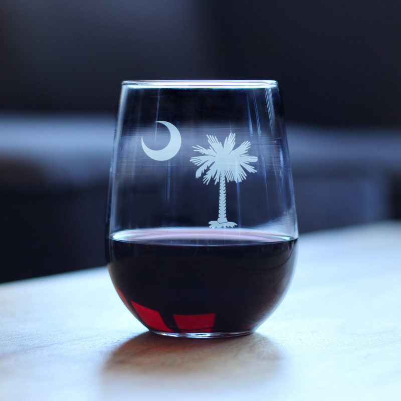Stemless wine glass with etched moon and palm tree, filled with dark red wine.